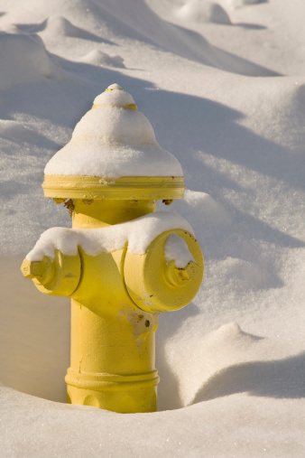 a yellow fire hydrant covered in snow..