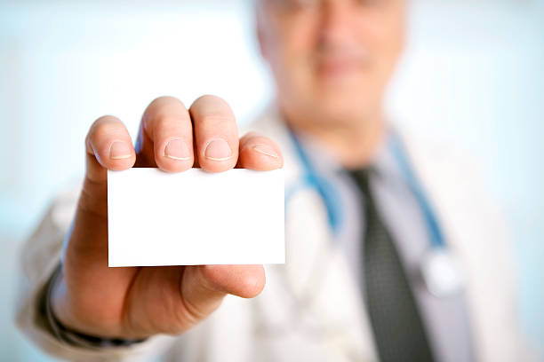 Doctor with stethoscope around his neck showing a blank card stock photo