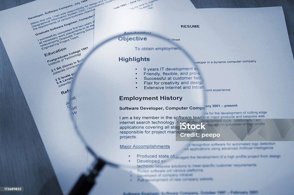 Magnifying Glass Examining Resume blue toned selective focus shot of resume and magnifying glass Résumé Stock Photo