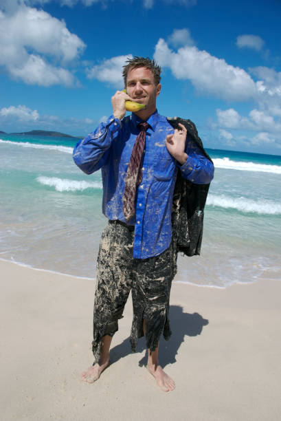 castaway sorridente de negócios fala no telefone de banana - stranded beached beach businessman imagens e fotografias de stock