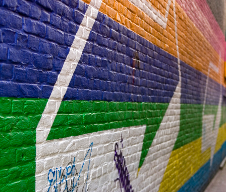 Brick wall in rainbow colors with white arrow