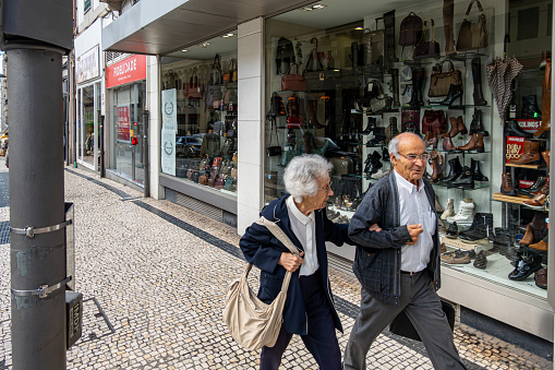 Porto, Portugal Sept 20, 2023 A senior couple walk arm in arm on the sidewalk in the downtown.