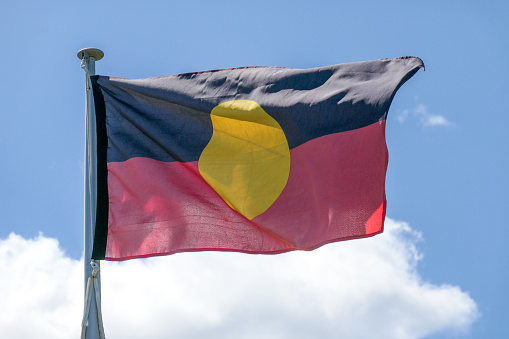 The Australian Aboriginal flag on one of the flagpoles outside Parliament House, Canberra.  This image was taken on a sunny afternoon on 8 October 2023.