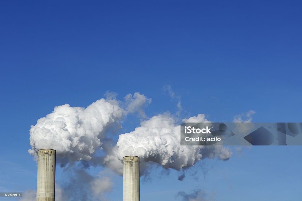 Two smoke stacks Two smoke stacks with pollution against blue sky Air Pollution Stock Photo