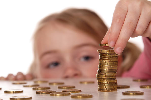 A child stacking coins on a table stock photo