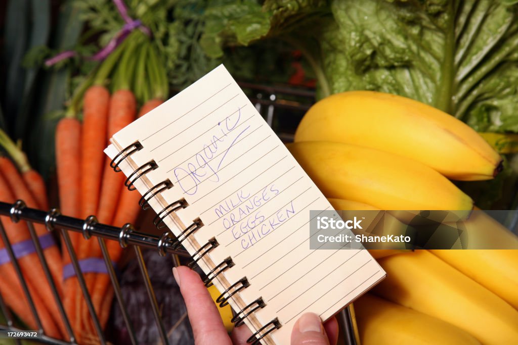 Organic Grocery Shopping List A woman checks her organic shopping list at a local Grocery Store Supermarket. Aisle Stock Photo