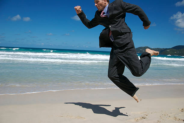 istock Businessman in Suit Leaps Along Tropical Beach 172694245