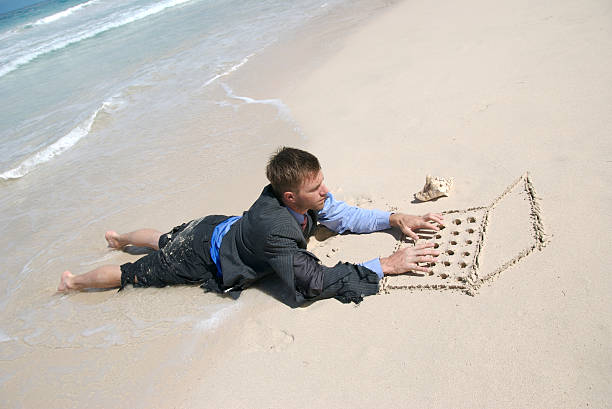 istock Castaway Businessman Lying on Beach Working Sand Laptop 172694398