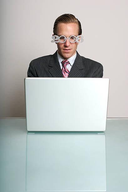 Businessman Wearing 2008 Glasses Sits at Computer