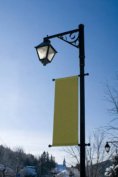 "A classic streetlight with a blank, verticle banner."