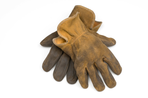 a pair of old well worn leather work gloves on 255 white background.