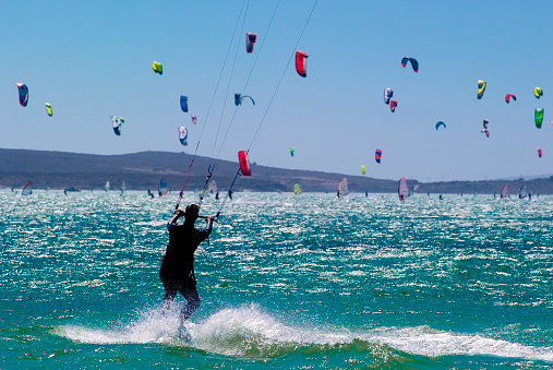 A kitesurfer surfs his board with hundreds of other sails.