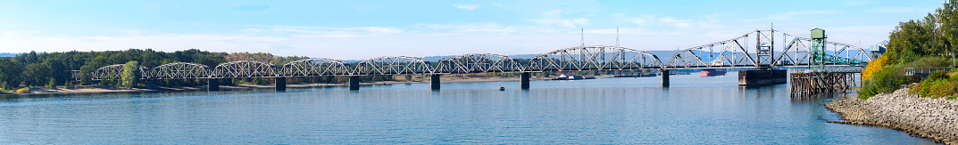 A panoramic view of the Columbia River with BNSF Railway Bridge 9.6 crossing from Vancouver, Washington to Portland, Oregon. The Columbia River that separates Oregon and Washington flows below the bridge.
