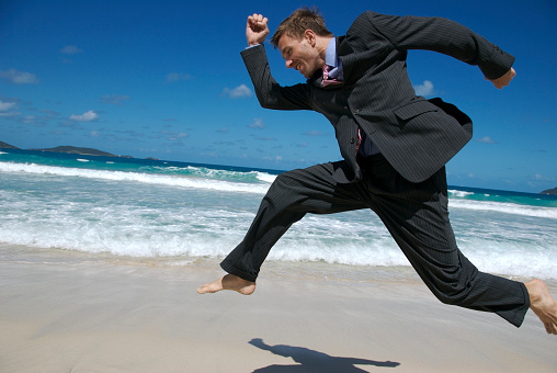 Young businessman taking a great leap forward on a tropical beach