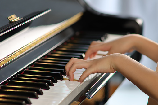 Children playing piano in the daytime with soft lighting. Proper hand posing.
