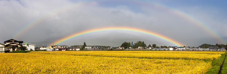 A bright vibrant double rainbow over the rural countryside of North Japan.