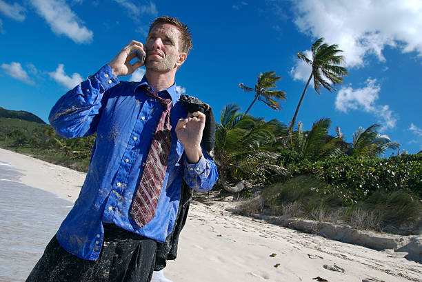 Yeah, I Flew Economy Businessman Stranded on Tropical Beach Wet and stranded businessman talks on his mobile phone on a deserted tropical island castaway stock pictures, royalty-free photos & images