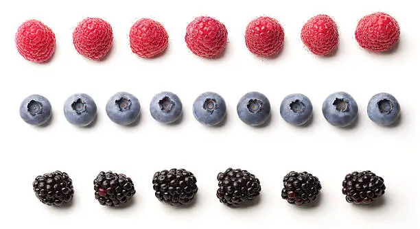 raspberries, blueberries, and blackberries lined up to create three  different fruit borders