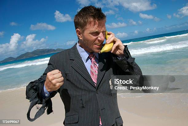 Frustrated Castaway Businessman Talks On Mobile Banana Stock Photo - Download Image Now