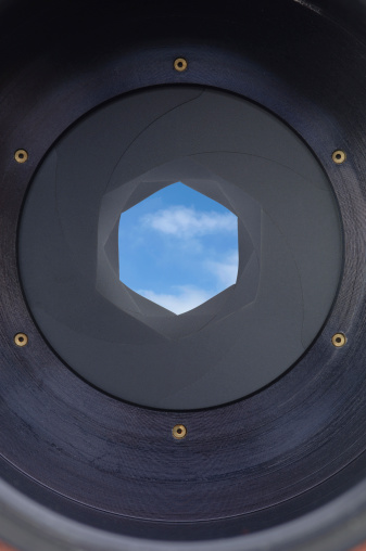 Viewing a Blue Sky with Puffy Clouds Through a Camera's Shutter.
