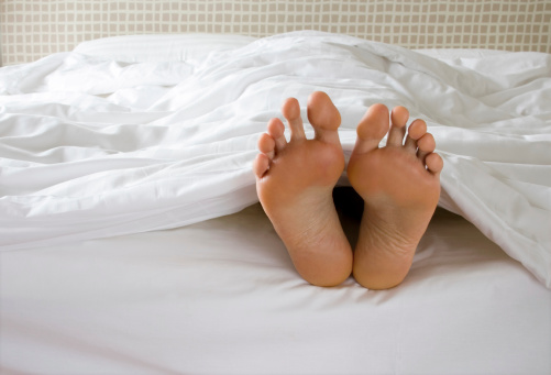 A man's feet poke out of the bottom of a white duvet in bed. Similar images from my portfolio:
