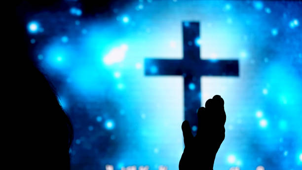 istock Silhouette hand raising, blurred christian cross background 1727007740