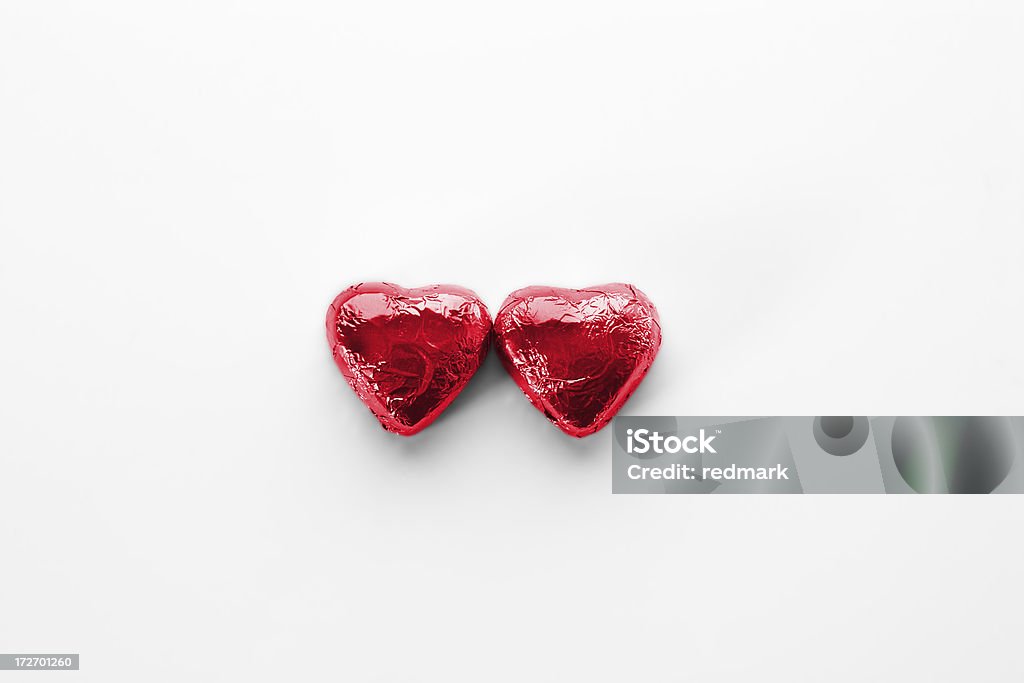 Two red hearts in love metaphor for two hearts in love using heart-shaped confectionary wrapped in shiny red foil and isolated; shallow depth of fieldSIMILAR IMAGES: Celebration Event Stock Photo