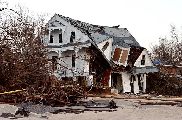 "Gorgeous old home in disrepair after Hurricane Katrina-  house has since been torn down.  Huge roots of tree exposed, and chunks of Beach Blvd lie in foreground."