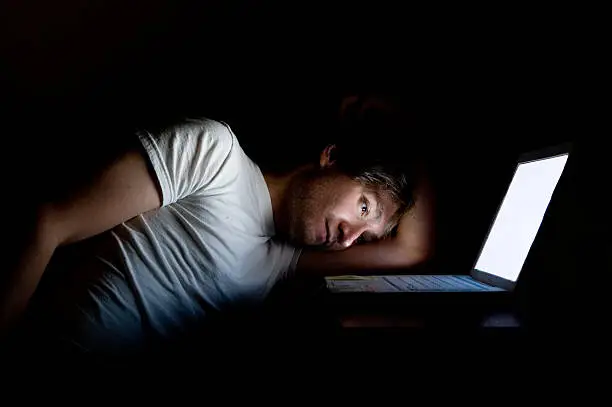 A man looks depressed by a computer late night.