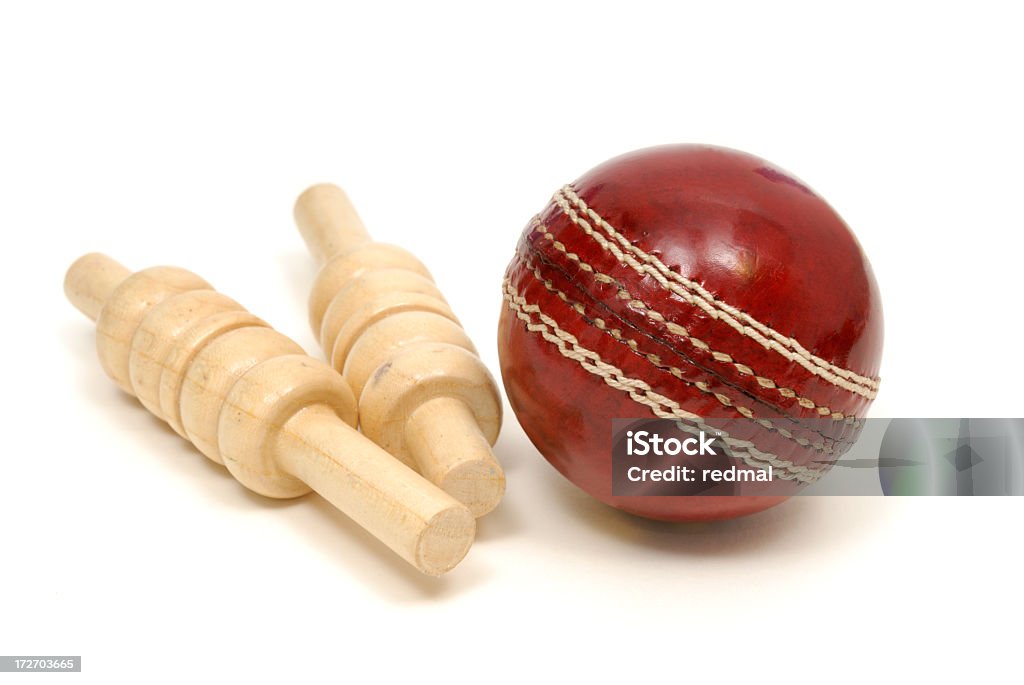 Close up of red leather cricket ball and two wooden bails  cricket ball and bails on white background Cricket Ball Stock Photo