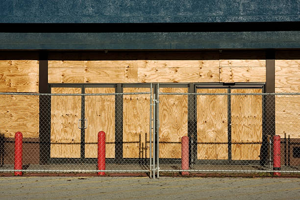 Abandoned Store Front view of an abandoned store with boarded windows and fence to keep trespassers out. boarded up photos stock pictures, royalty-free photos & images
