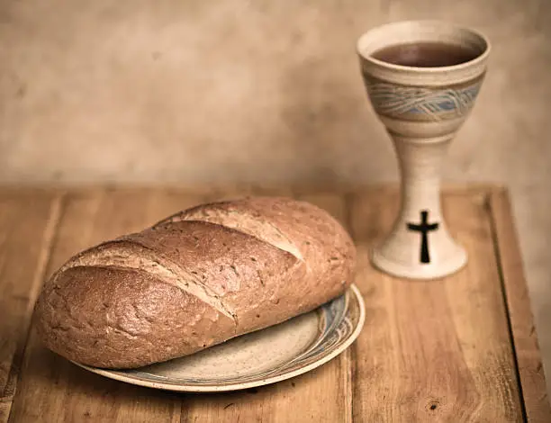 Vintage look communion with bread in focus and chalice in background. Communion with Wine and Bread. 