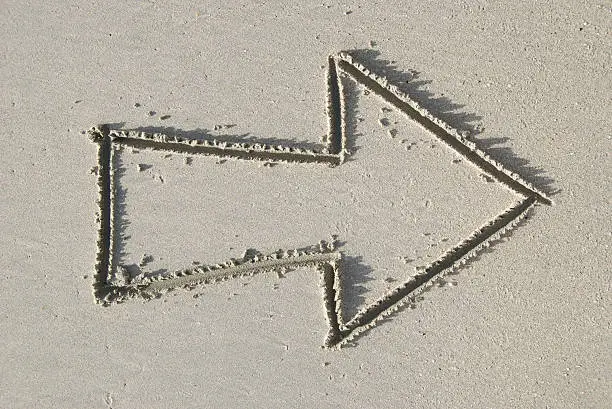 Chunky arrow drawn in fine gray sand