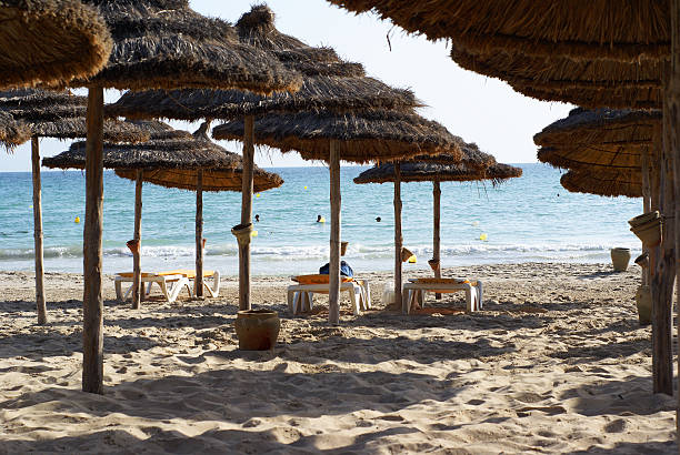 Under the shadow of straw umbrellas View to the sea from the beach with umbrellas. Focus on distant objects.This and other images in tunisia beach stock pictures, royalty-free photos & images