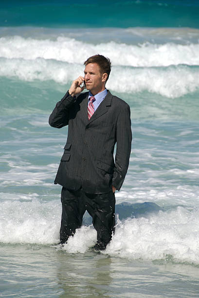 hombre está hablando por teléfono móvil en big surf - stranded men telephone beach fotografías e imágenes de stock