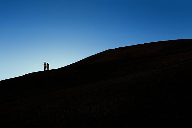 Silhouette of Couple on a Hill at Night stock photo