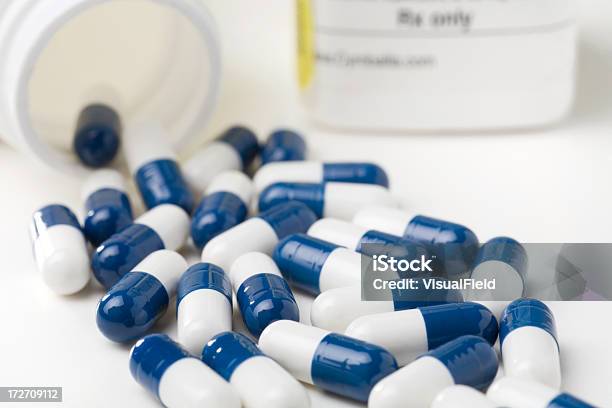 Medicine Capsules Spilled From Prescription Bottle Stock Photo - Download Image Now - Blue, Pill Bottle, White Background