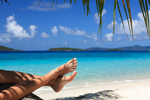woman with sandy feet relaxing on a tropical beach in the Caribbean