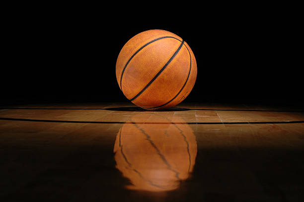 istock Basketball lying on shiny court against black background 172709485