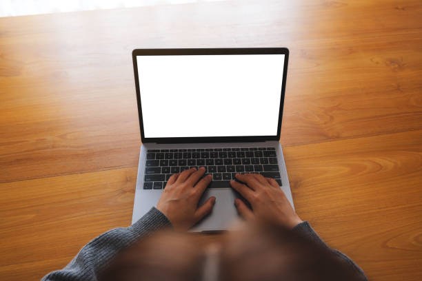 istock Top view mockup image of a woman working and typing on laptop computer with blank screen on wooden table 1727109036