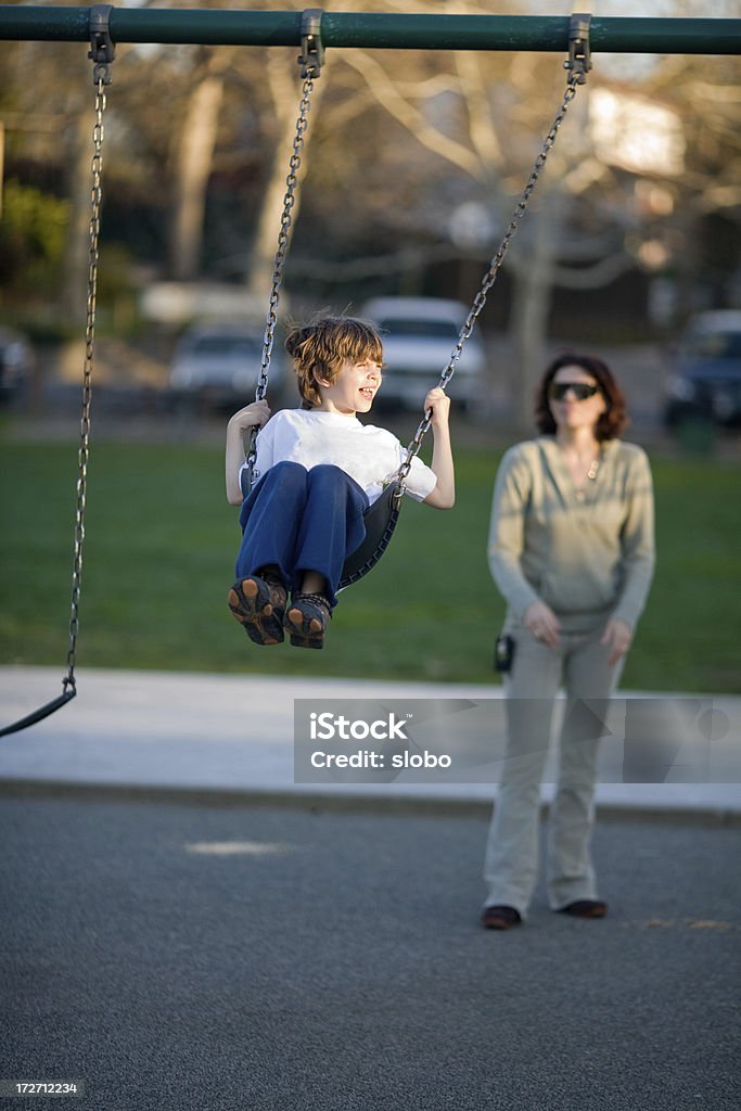 Junge auf Schaukel mit aufmerksamen Mutter - Lizenzfrei Kind Stock-Foto