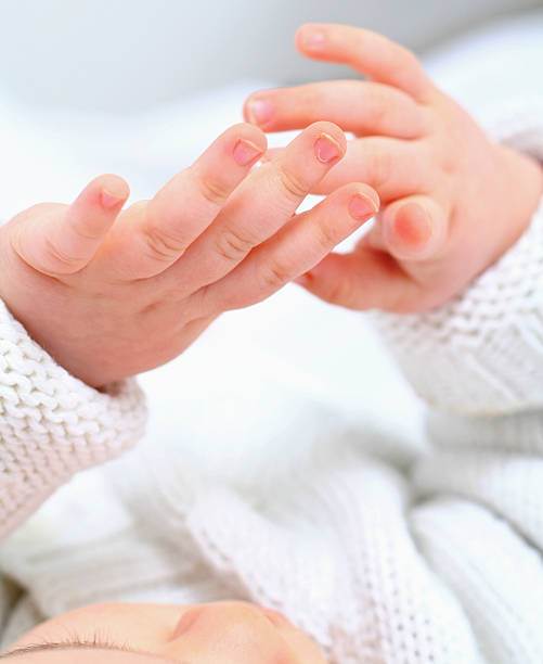 Close-up view of an infant focused on her hands stock photo
