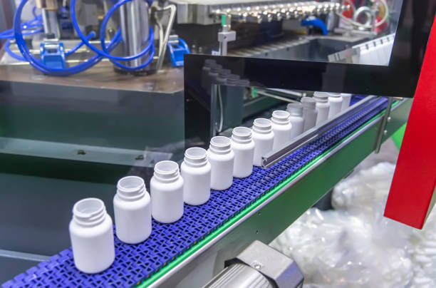 istock Moving polypropylene white bottles on conveyor belt of automatic liquid filling machine 1727130817