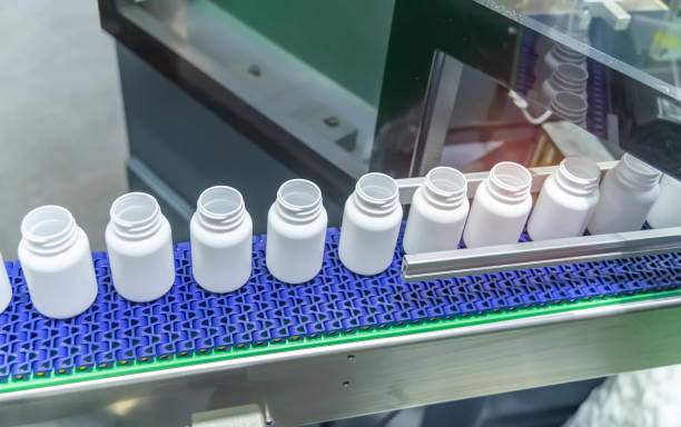 istock Moving polypropylene white bottles on conveyor belt of automatic liquid filling machine 1727131391