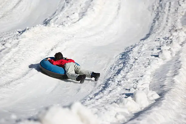 Young Boy Sledding Down a Snow-Covered Hill on a Rubber Ring