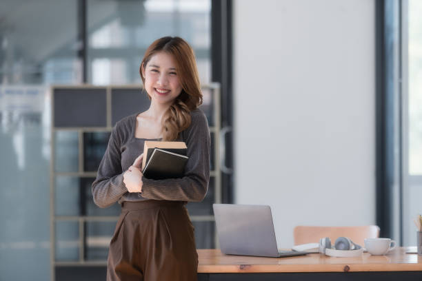 istock Pretty young Asian college student standing while holding books. Back to school concept. 1727150643
