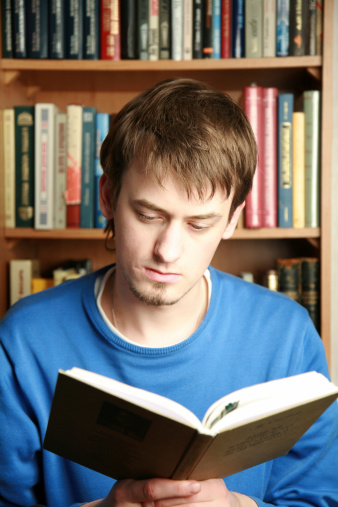 man holding a book and looking surprised