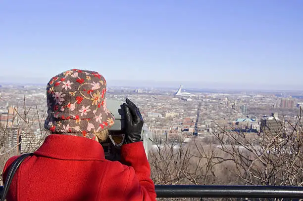 Tourist on Mount Royal in Montreal Quebec using binoculars to see the Olympic Stadium and the St. Lawrence Seaway. (Fleuve St. Laurent)