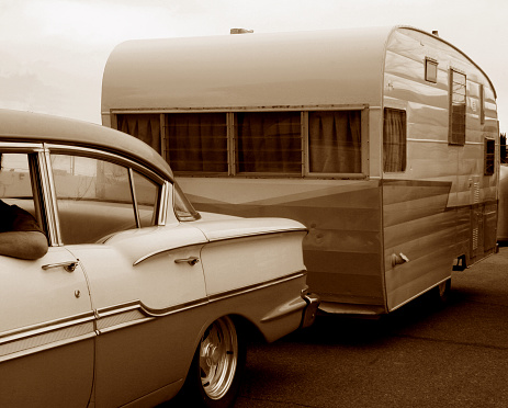 vintage automobile towing vintage travel trailer, in sepia