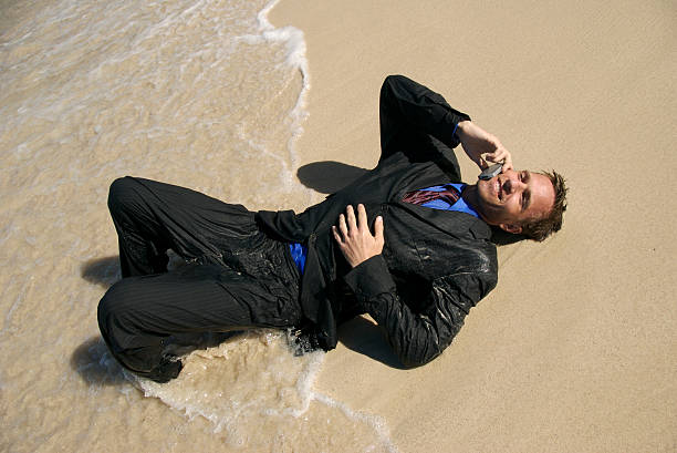 hombre s'encuentra en las olas hablando por su teléfono - stranded men telephone beach fotografías e imágenes de stock